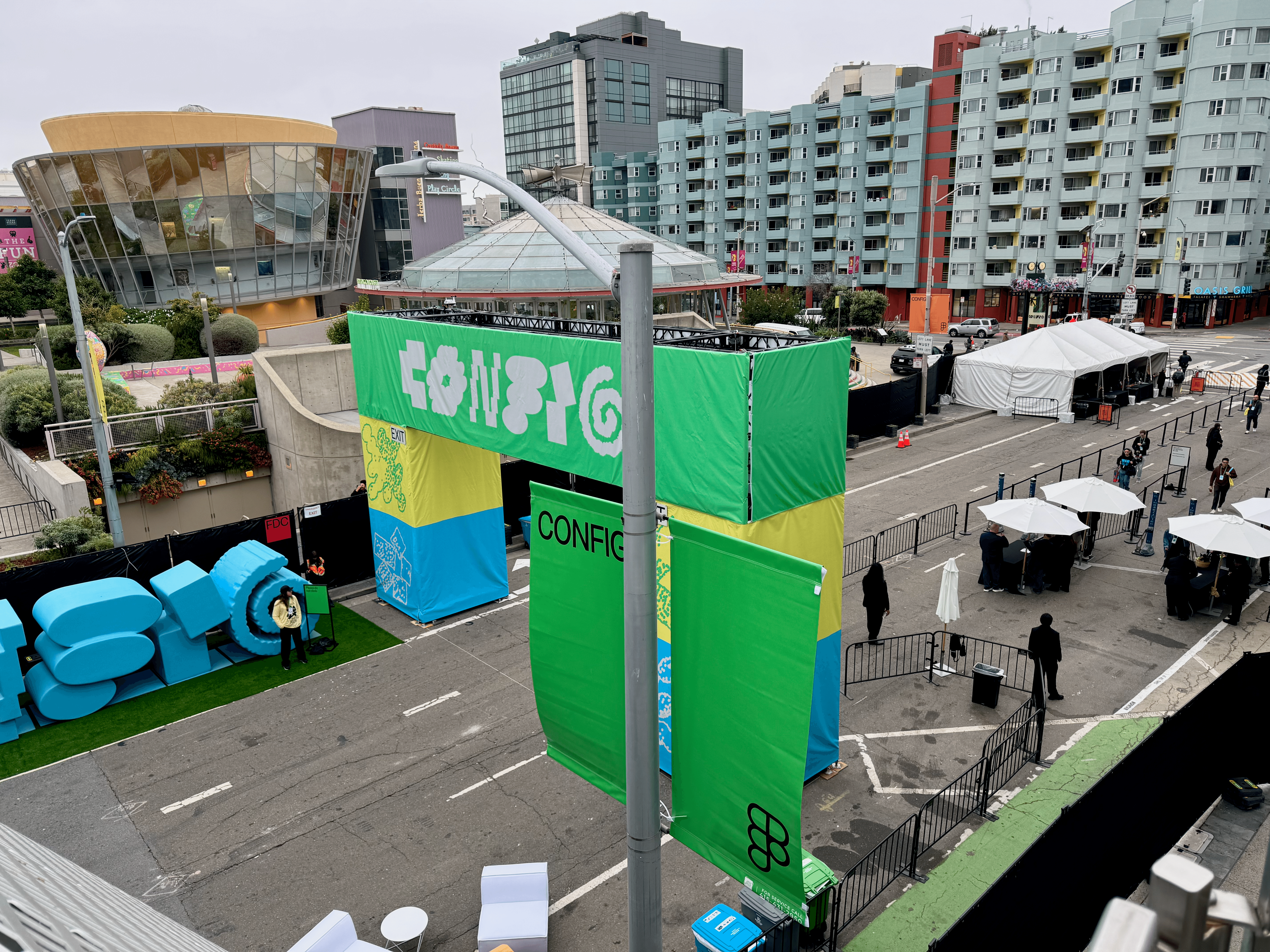 An aerial view of a large green Config archway over a San Francisco street, with an outdoor registration area and queue below