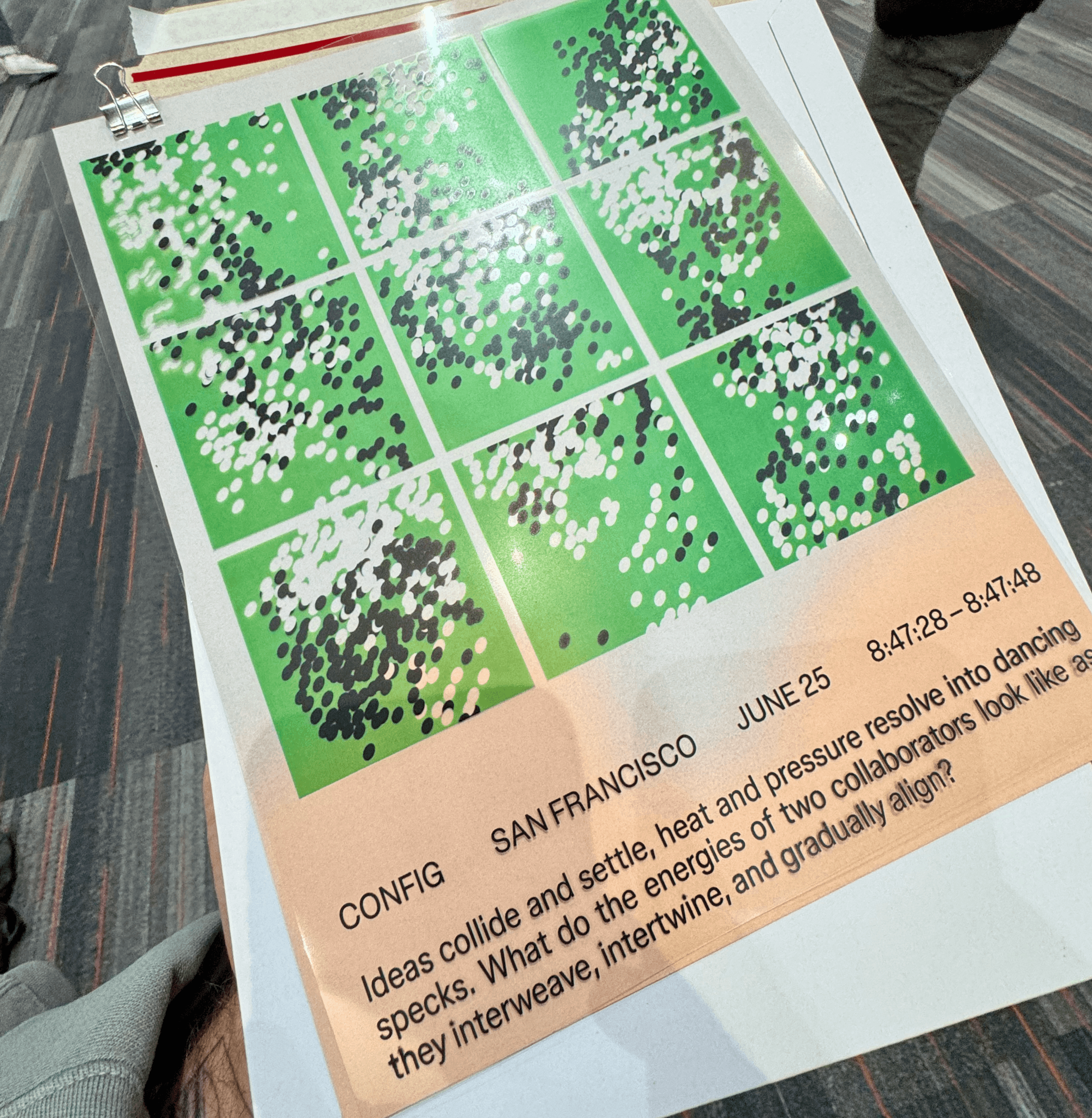 A printed card from the Shared Frequencies installation showing a grid of green, black, and white dot patterns with the prompt 'ideas collide and settle, heat and pressure resolve into dancing specks'