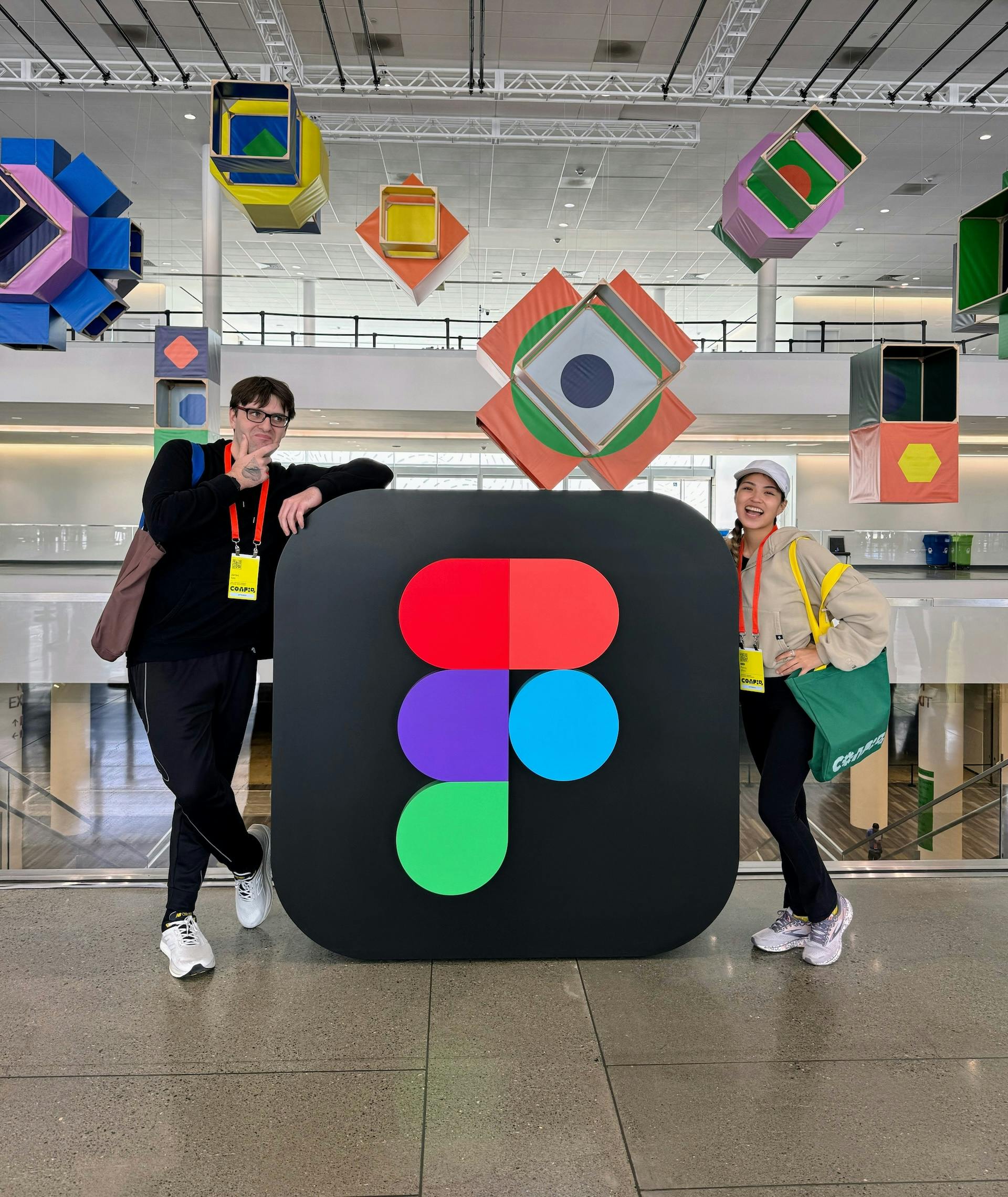 Two people standing left and right of a large Figma 'F' logo